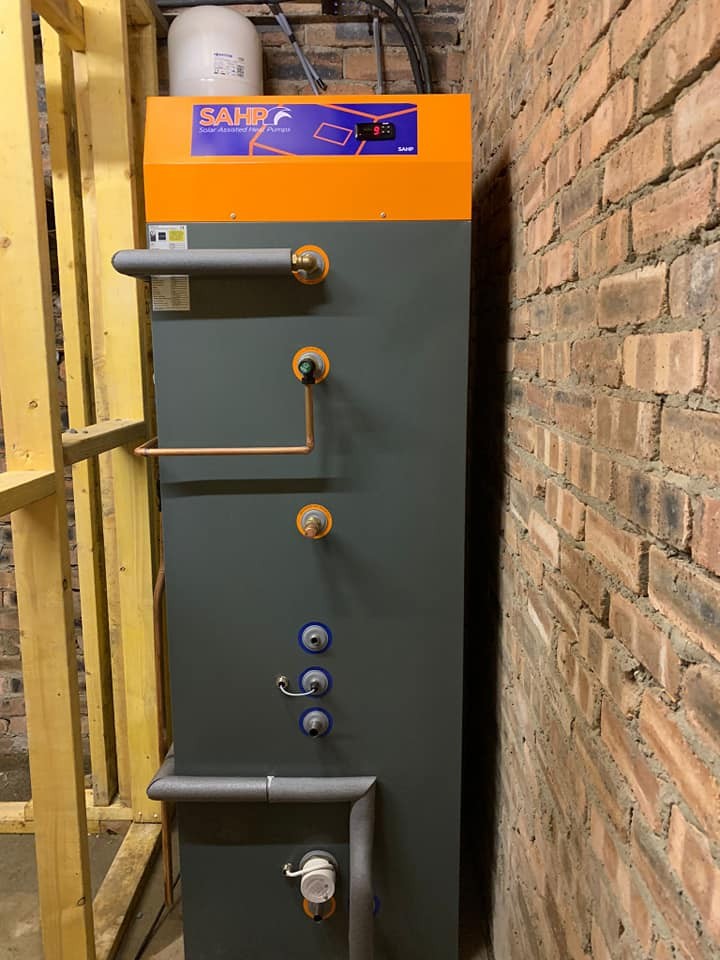 Solar Assisted Heat Pump unit installed against a brick wall. It is part of a heating system in a building