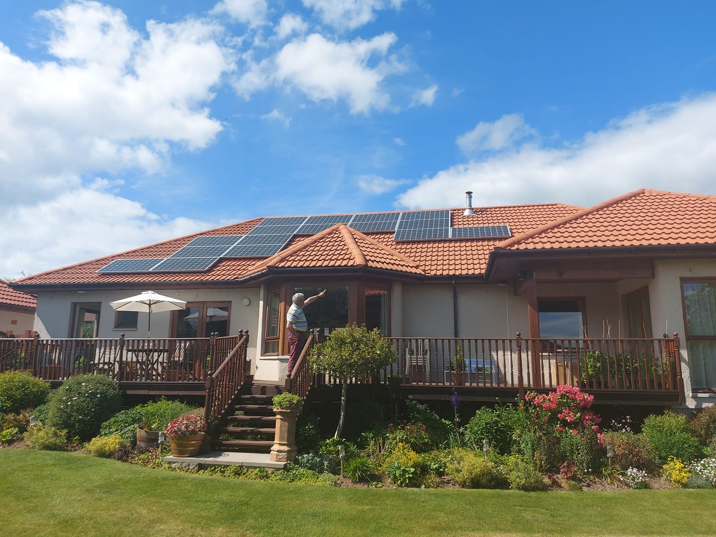 PV Panels installed on a roof of a domestic house and a happy man pointing to the result