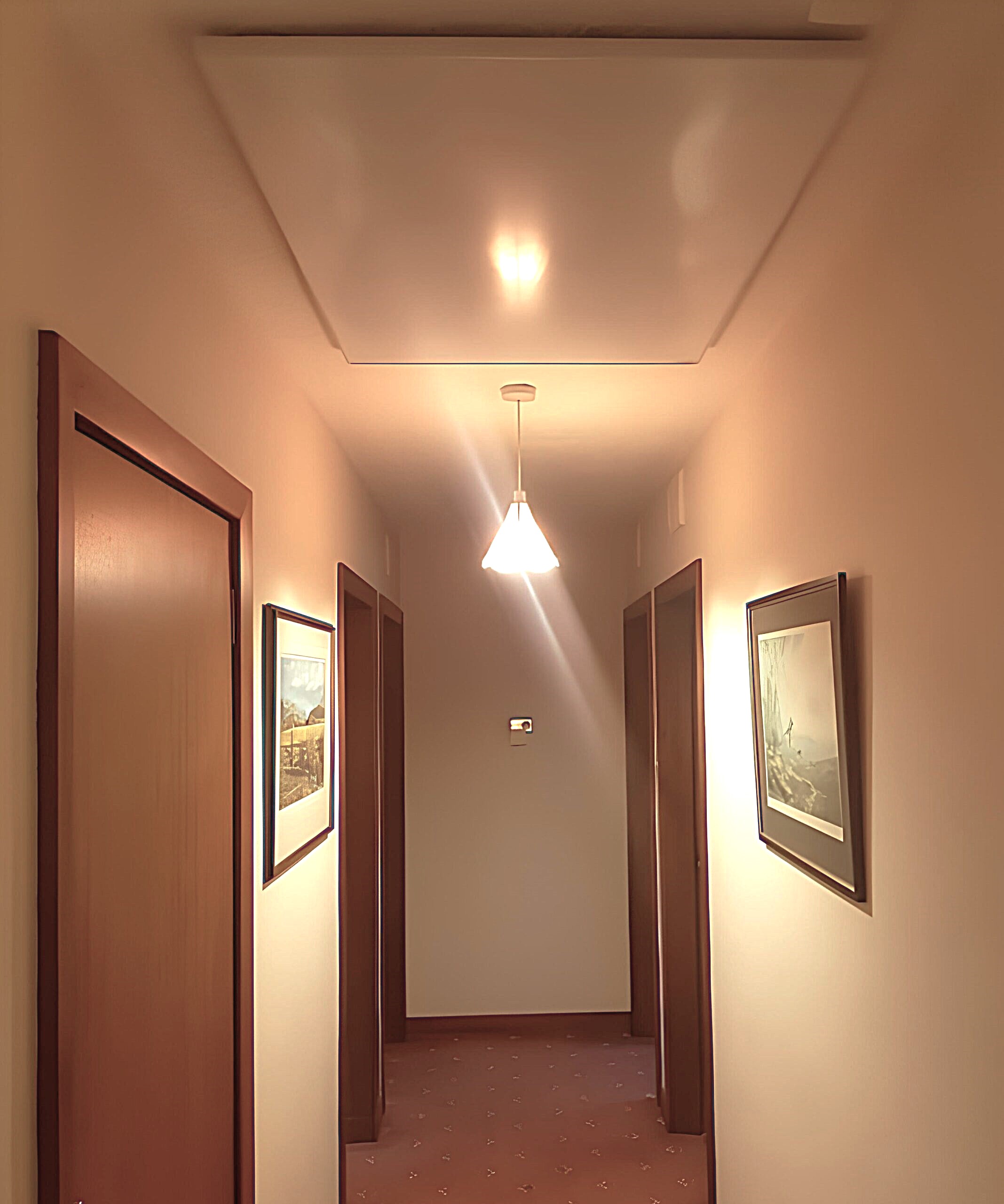 White infrared heater mounted on the ceiling in a hallway.