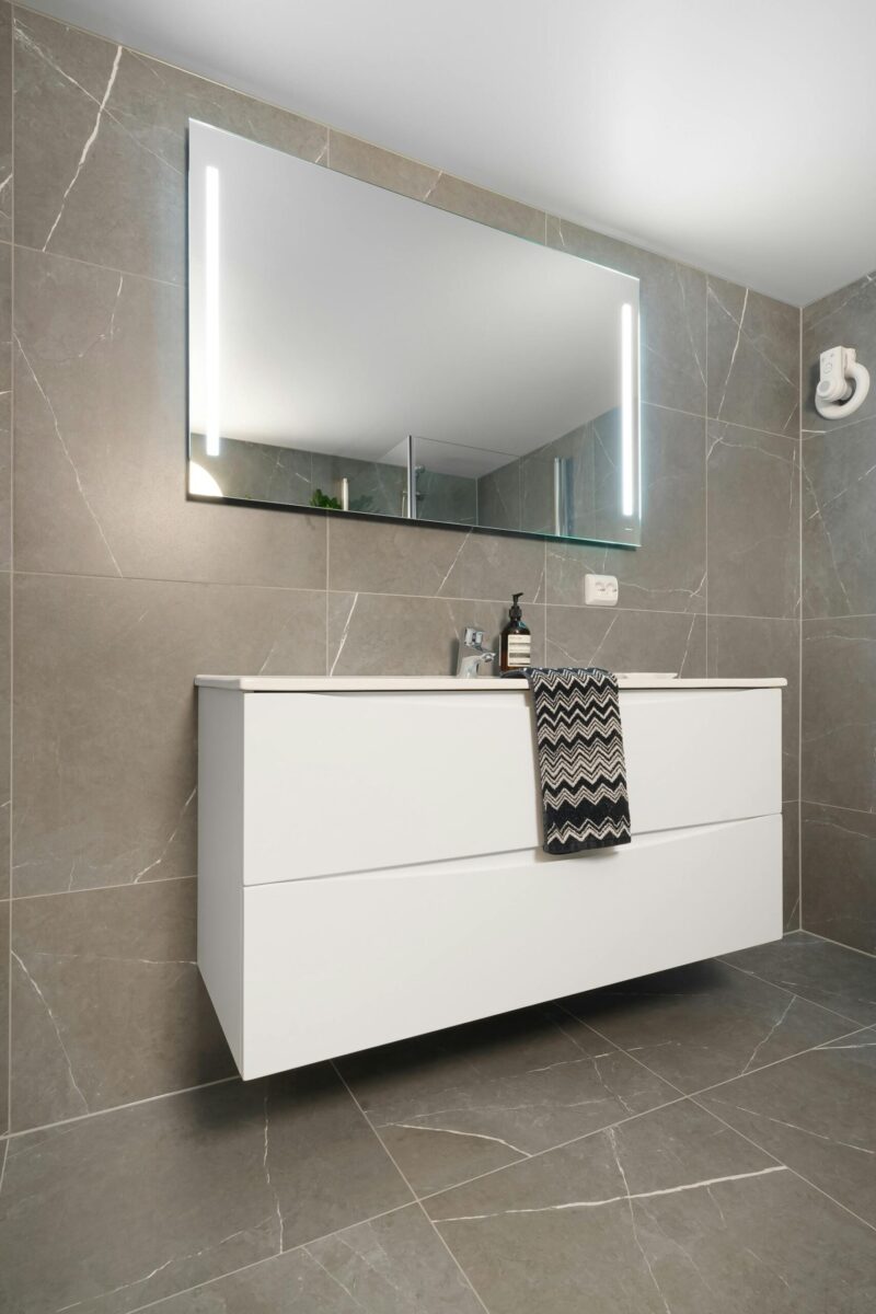 White electric panel heater mounted on a wall with a shelf above it.