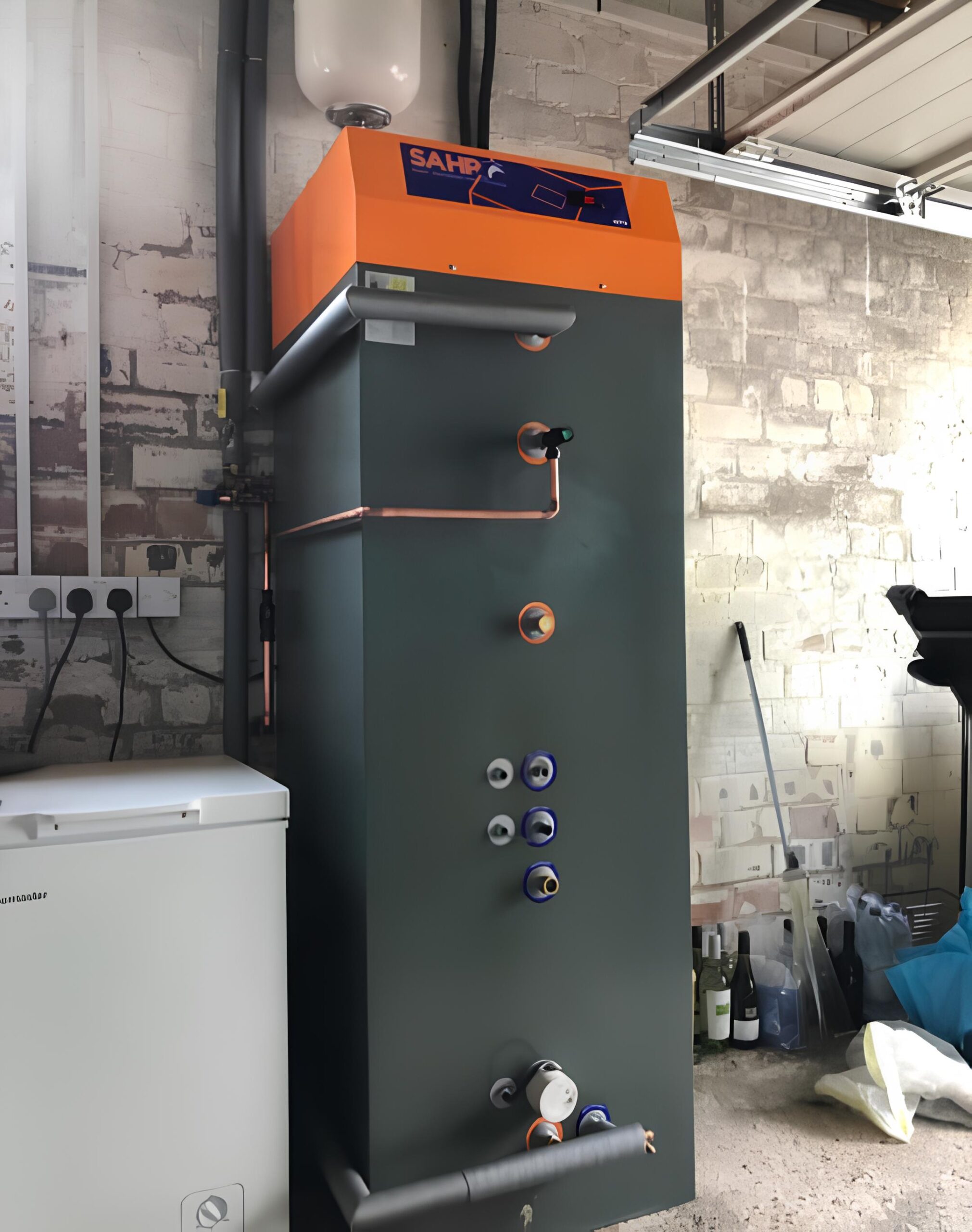 Solar water heater tank with orange SAHP logo, installed in a garage in Fife.