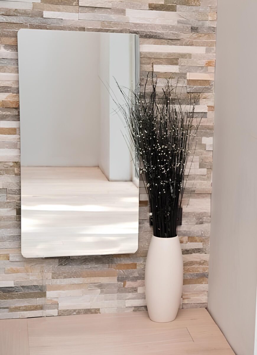 Photo of a large mirror heater installed on a wall with a decorative stone tile accent wall.